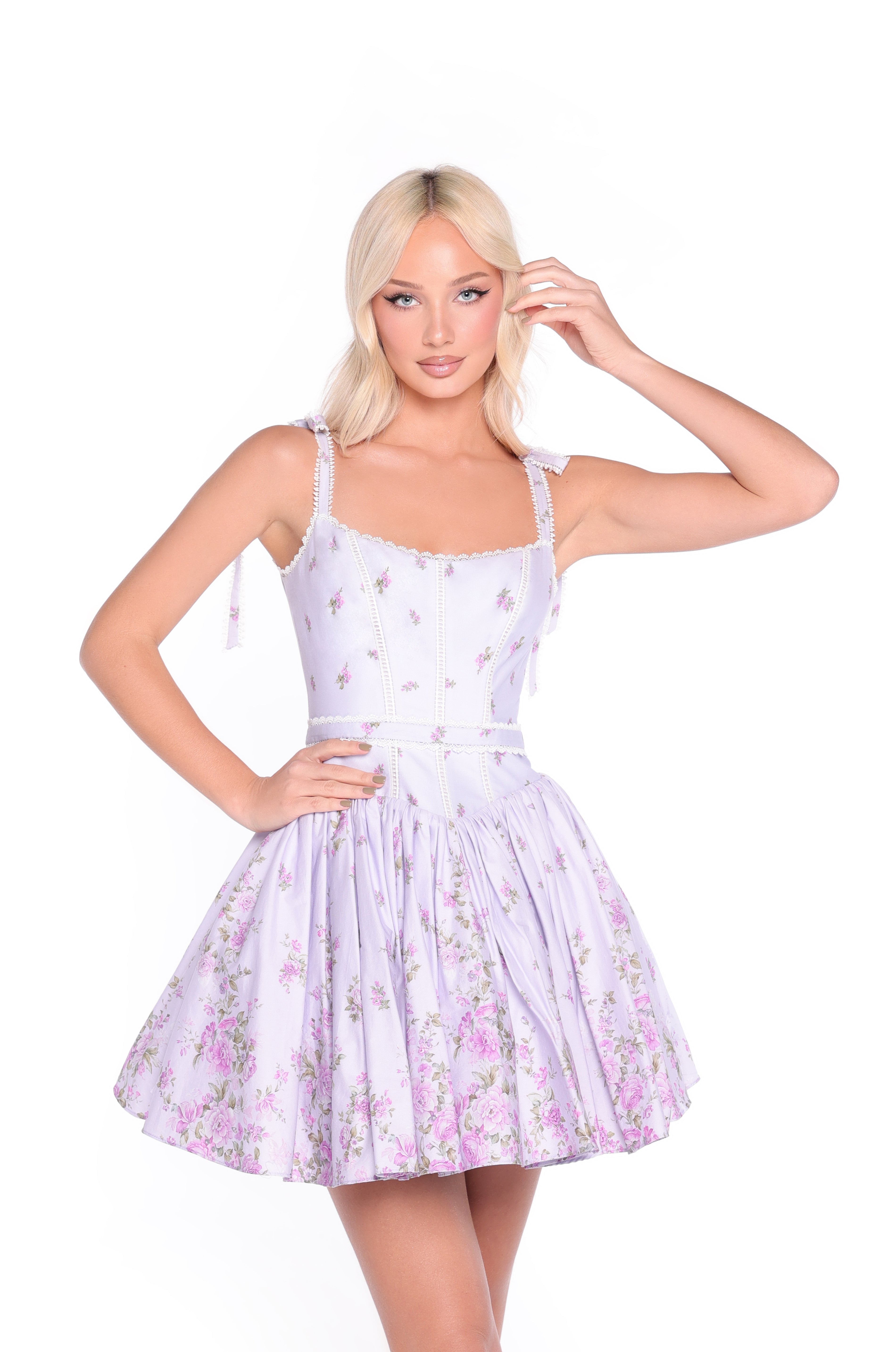 A woman with blonde hair wears the Lilac Floral Short Casual Dress: Mila, featuring a fitted bodice and flared skirt, standing against a white background.